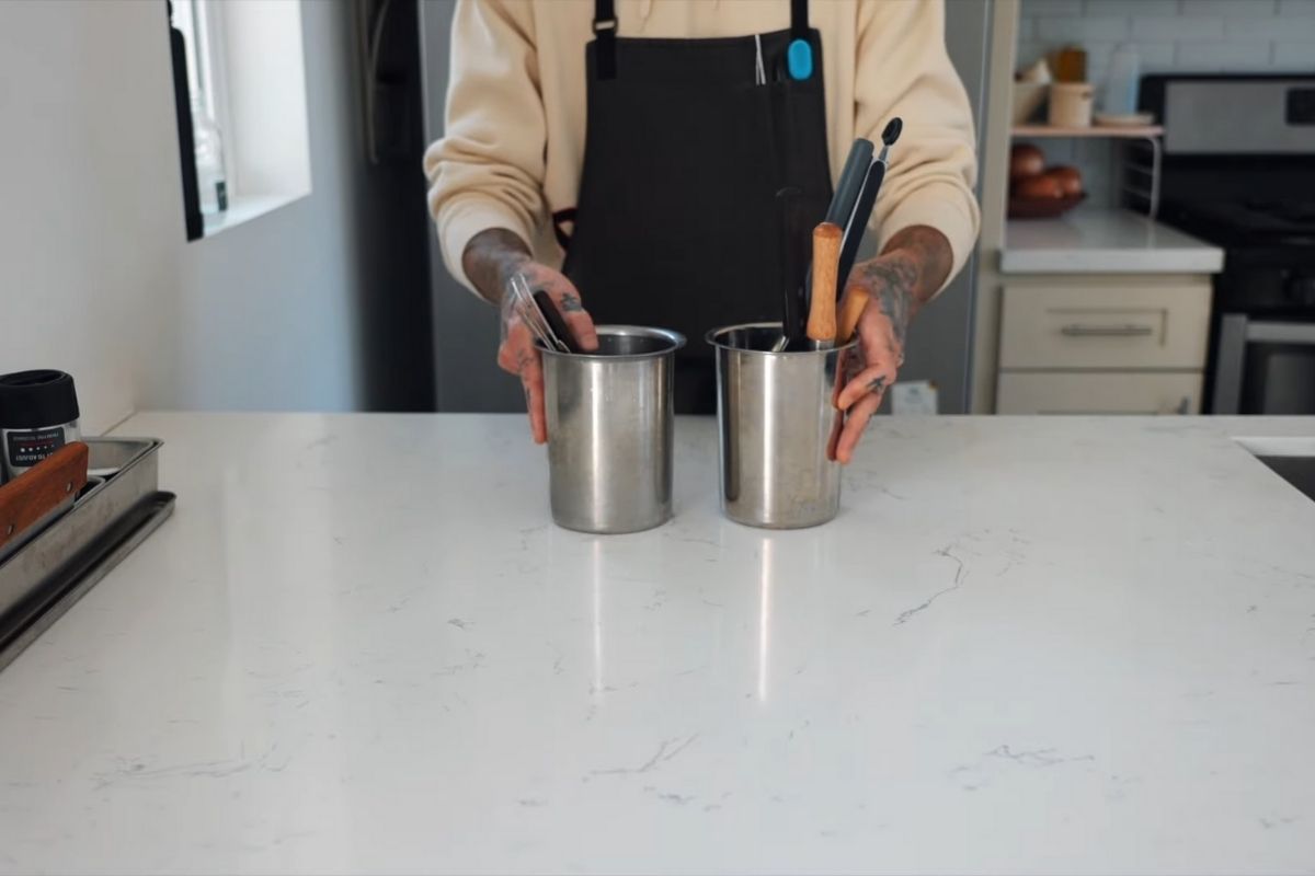 Osoba u kuhinji priprema pribor za kuvanje dok muzika stvara prijatnu atmosferu